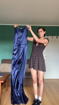 Abito in raso blu navy con design senza maniche, silhouette fluida e vita; texture liscia e finitura lucida.