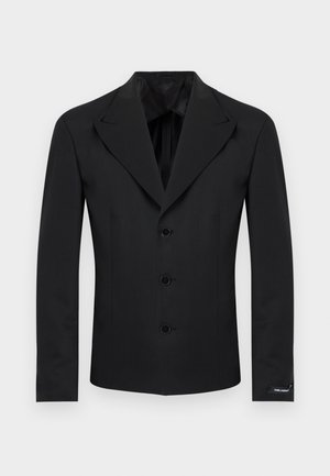 Melns piegriezts žakete ar notiņām atlokos, trim priekšējiem pogām, gariem piedurknēm un nelielu logotipa birku uz kreisā aproces.