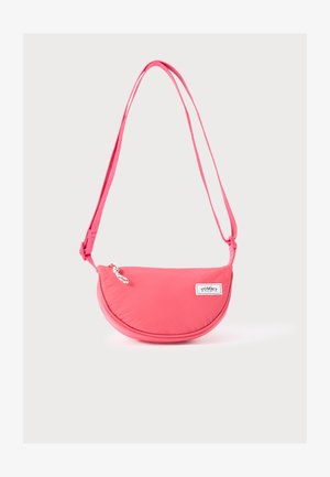 Roze crossbodytas met een afgeronde vorm, gemaakt van zachte stof, voorzien van een logopatch, een verstelbare riem en een ritssluiting.