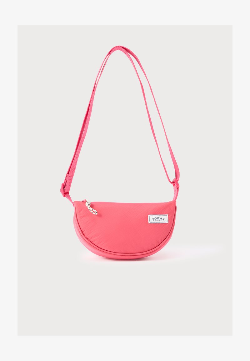 Różowa torebka na ramię o zaokrąglonym kształcie, wykonana z miękkiego materiału, z naszywką z logo, regulowanym paskiem i zamkiem błyskawicznym.