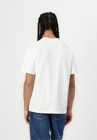 White cotton t-shirt with short sleeves, crew neckline, and a relaxed fit. Back view shows smooth texture and basic design.