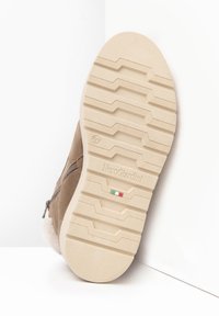 Beige Wildleder-Ankle-Boots mit weißem Fellfutter, seitlichem Reißverschluss und einer strukturierten cremefarbenen Gummisohle mit gerilltem Muster.