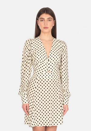 Abito a pois, tessuto crema con pois neri, scollatura a V profonda, maniche lunghe a sbuffo, vita aderente e lunghezza sopra il ginocchio.