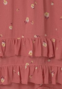 Rosa geblümter Stoff mit gerafften Stufen. Verziert mit kleinen gelben und weißen Blumen auf einem strukturierten, leichten Material. Weiche, zarte Oberfläche.