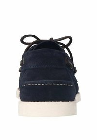 Marineblauwe suede schoen met een platte witte zool, ronde neus en bruine veters; heeft decoratieve stiksels en metalen accenten aan de zijkanten.