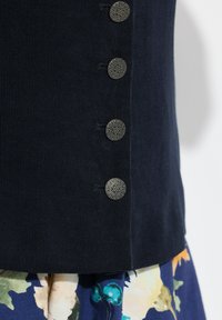 Marineblauw geribbeld topje met vijf decoratieve zilveren knopen aan de zijkant, gecombineerd met een onderstuk met bloemmotief.