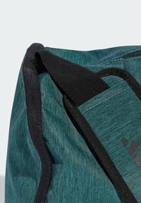 Cyan kleurige stoffen reistas met zwarte accenten, voorzien van een gedetailleerde textuur, versterkte stiksels en een klein zwart logo aan de zijkant.