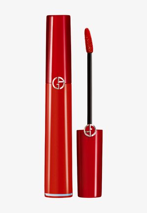 Lápiz labial rojo con un tubo brillante y un aplicador. El envase presenta un logotipo circular prominente y un acabado suave y brillante.
