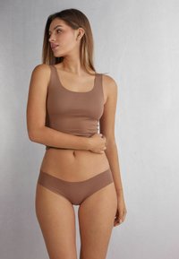 Débardeur marron sans coutures et culotte assortie avec une texture lisse, dotés d'un décolleté carré et d'une taille élastique. Fond neutre.