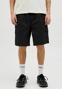 Pantaloni scurți negri de tip cargo, cu buzunare laterale, confecționați dintr-un material durabil. Purtați cu șosete albe și pantofi sport negri. Design simplu și funcțional.