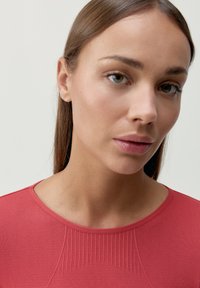 Czerwona dopasowana bluzka z okrągłym dekoltem i teksturowanym rypsowym wykończeniem na klatce piersiowej. Gładki materiał o subtelnej połysku.