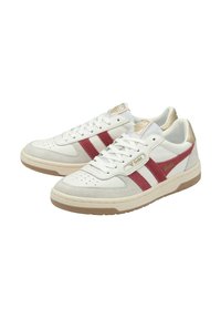 Sneakers bianchi con strisce rosse e un accento dorato. Realizzati in pelle e suede, presentano dettagli forati e una suola piatta in gomma.