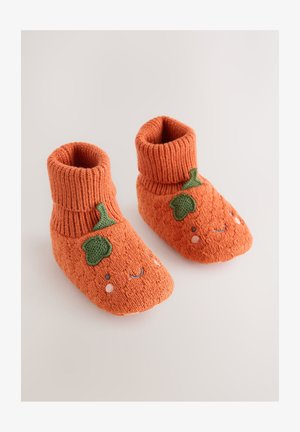 Narančaste pletene papučice s naboranim manšetama, ukrašene izvezenim zelenim listom i detaljima osmijeha na prstima za razigrani dizajn.