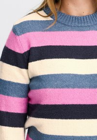 Pull rayé avec des bandes alternées de rose, marine, crème et bleu clair. Fabriqué en tricot doux et texturé avec un col côtelé.