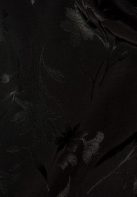 Tissu noir avec des motifs floraux sombres subtils créant un design texturé et élégant avec des formes de feuilles et de fleurs.