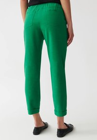 Groene, elastische broek met een rechte pijpdesign, opgerolde mouwen en twee achterzakken. Glad textuur en een levendige kleur.