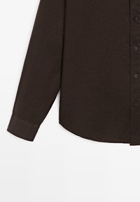 Dark brown long-sleeve shirt with buttoned cuff and front button placket, displayed against a white background.