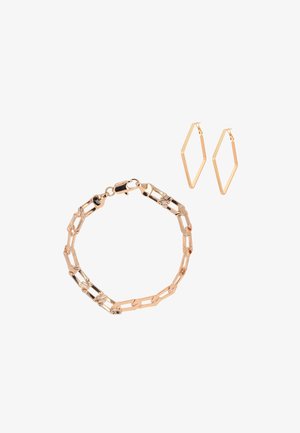 Bransoletka w kolorze złota z teksturowanymi, wydłużonymi ogniwami oraz pasujące geometryczne kolczyki-koła w kształcie diamentu na białym tle.