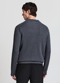 Dunkelgrauer, gerippter Pullover mit Kragen, ausgestattet mit langen Ärmeln und einer lockeren Passform. Das Material hat eine weiche Textur und ein dezentes Muster.