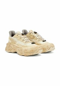 Scarpe da ginnastica beige con finitura testurizzata, suola spessa, dettagli in mesh e lacci elastici fissati da una regolazione a scatto.