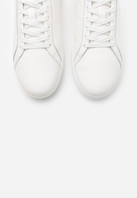White leather sneakers with a smooth finish, rounded toe, and flat laces. Subtle side stitching and rubber outsole.