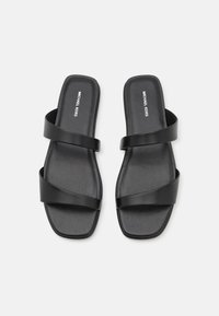 Des sandales noires à glissière avec un design ouvert au niveau des orteils. Deux larges brides croisent le pied, présentant une texture lisse et une semelle de forme carrée.