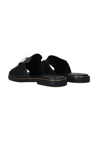 Chaussures slip-on noires en tissage avec une semelle plate et des accents dorés. Présentent un dos ouvert et un upper texturé pour la respirabilité.