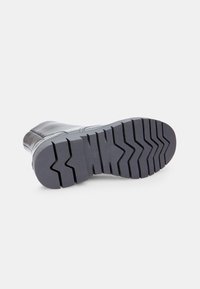 Botă din piele lacuită neagră, cu o talpă din cauciuc masivă, având un model texturat pentru aderență și stabilitate.
