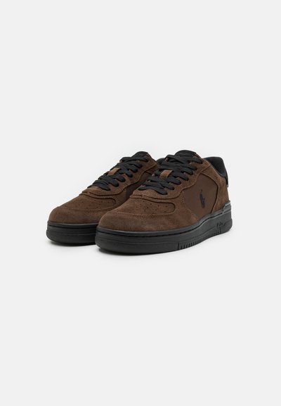 Bruine suède sneakers met zwarte accenten, ronde neus, geperforeerde details en zwarte veters, met een logo op de zijkant. Rubberen zool.