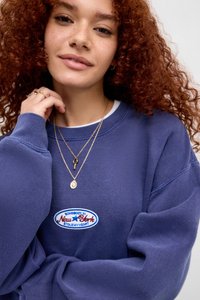 Tamno plavi oversized dukserica s vezom na kojoj stoji "Neko iz New Yorka ukrao mi je srce," s rebrastim manžetama i mekanom teksturom.
