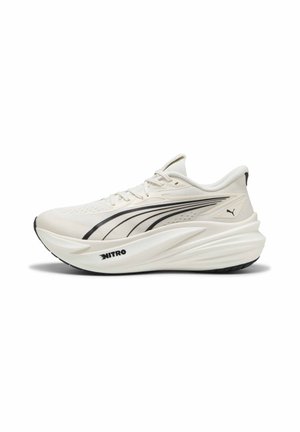 Chaussure de course Puma blanche avec des bandes de logo noires, une semelle épaisse et amortie portant l'inscription « NITRO », et une fermeture à lacets, vue de côté sur fond blanc.
