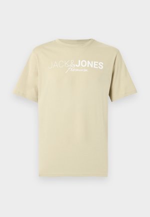 T-shirt beige à manches courtes avec le texte blanc "JACK & JONES premium" imprimé sur la poitrine sur un fond uni.