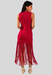 Vestido de punto rojo con un diseño sin mangas y un dobladillo largo con flecos. Cuenta con una superficie texturizada y se combina con cuñas de esparto.