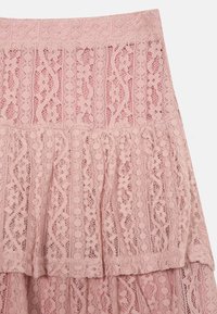Rosa blonde skjørt med lagdelte volanger og intrikate mønstre av bølger og sirkler. Myk tekstur med detaljer i bølgekant.