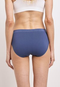 Blå sömlös hipsterunderdel med en slät textur och bred midjeband, med en medelhög skärning och figurnära design.