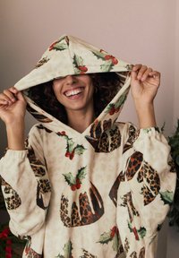 Kapuutsiga dressipluus pehmest kreemjast kangast, millel on pidulik mustriline jõulupudingu, vahtralehe ja punaste marjadega, ning elastsete mansettidega.