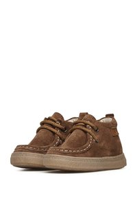Scarpe in suede marrone con cuciture beige, punta rotonda e design con lacci. Caratterizzate da una suola in gomma testurizzata e da una piccola etichetta con logo sul lato.