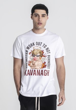 Jeune homme portant un T-shirt blanc avec un ange musclé soufflant du chewing-gum et le texte "Tu ferais mieux de t'entraîner pour ne pas t'épuiser" et "Kavanagh."