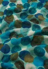 Tessuto trasparente con uno sfondo teal che presenta motivi circolari in tonalità di blu, verde e marrone, creando un aspetto testurizzato.