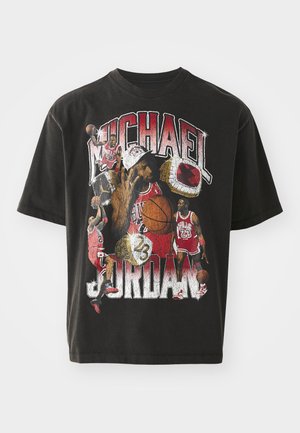 Musta puuvillapaita, jossa on kollaasia Michael Jordanista eri hetkissä, sekä rohkeaa tekstiä ja eloisia grafiikoita punaisilla, valkoisilla ja keltaisilla yksityiskohdilla.