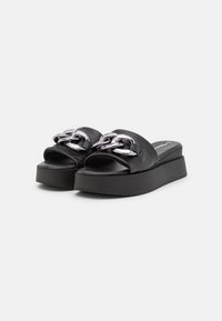 Sandales glissières en cuir noir avec une semelle plateforme épaisse, ornées d'un détail chaîne argentée sur la bande. Texture lisse avec un design à bout ouvert.