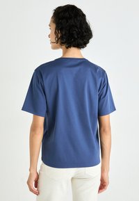 Navyblauwe katoenen t-shirt met een ontspannen fit, korte mouwen en een klassieke ronde hals. Soepele textuur en eenvoudig ontwerp.