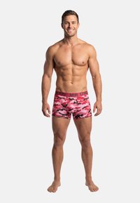 Boxer camouflage rose avec une taille élastique noire, présentant une coupe ajustée et un matériau en spandex pour l'élasticité.