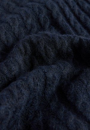 Tmavě námořnická pletená tkanina s měkkým, texturovaným povrchem, který má jemný vzor pleteného kabelu. Materiál vypadá teple a útulně.