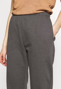 Grå sweatpants med elastisk midja, sidofickor och en mjuk, slät textur. Klippt för en avslappnad passform, med minimala detaljer.