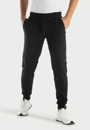 Zwarte joggerbroeken van zachte stof, met een elastische tailleband met trekkoord, zijzakken en geribbelde boorden aan de enkels.