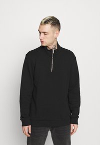 Zwarte zip-up sweatshirt met hoge kraag, voorzien van een zilveren rits, lange mouwen en geribde manchetten en onderrand. Gladde textuur, casual ontwerp.