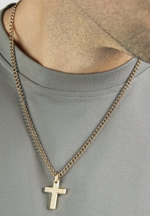 Gold-tone chain necklace featuring a polished cross pendant, worn over a gray crewneck shirt. Chain has a classic round link design.