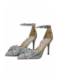 Zapatos de tacón alto plateados con punta afilada, adornados con un detalle de lazo, cubiertos de brillantes strass, con correa al tobillo y tacón de aguja.