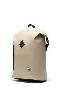 Beige waterproof backpack with a roll-top design, black zipper, and diamond accent. Features a contrasting black base and logo patch.